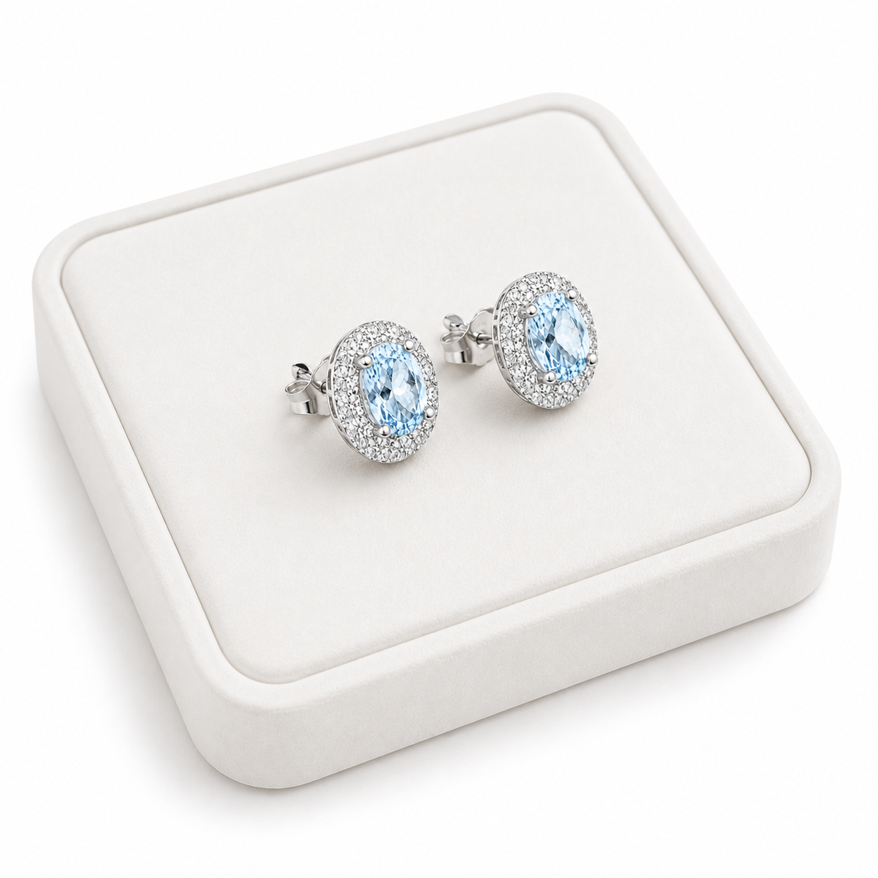Natural Sky Blue Topaz oval halo earrings displayed on luxury white jewelry tray