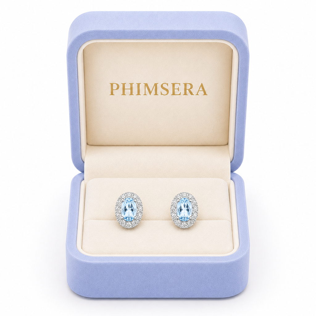 Phimsera 4x6mm Sky Blue Topaz halo stud earrings presented in luxury jewelry gift box