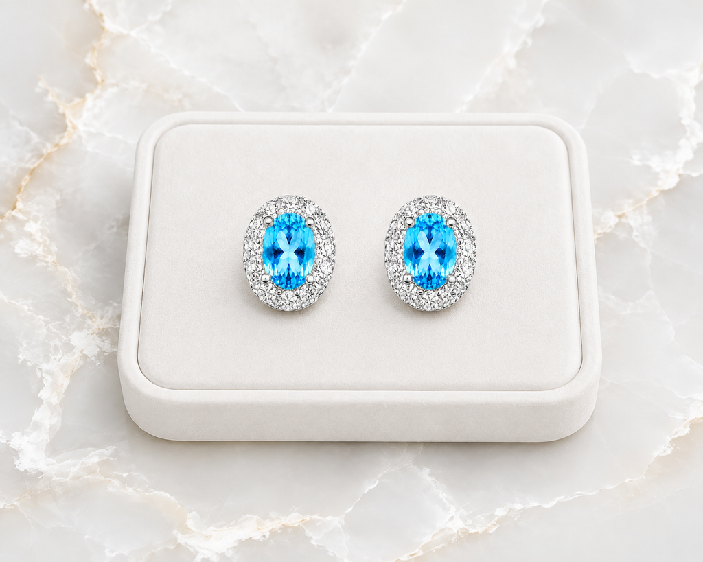 4x6mm Swiss Blue Topaz earrings displayed on a white jewelry tray over luxury marble