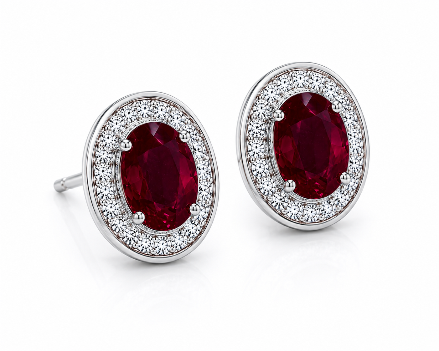 Natural 4x6mm oval ruby halo stud earrings in platinum plated 925 sterling silver with sparkling cubic zirconia on a white background.