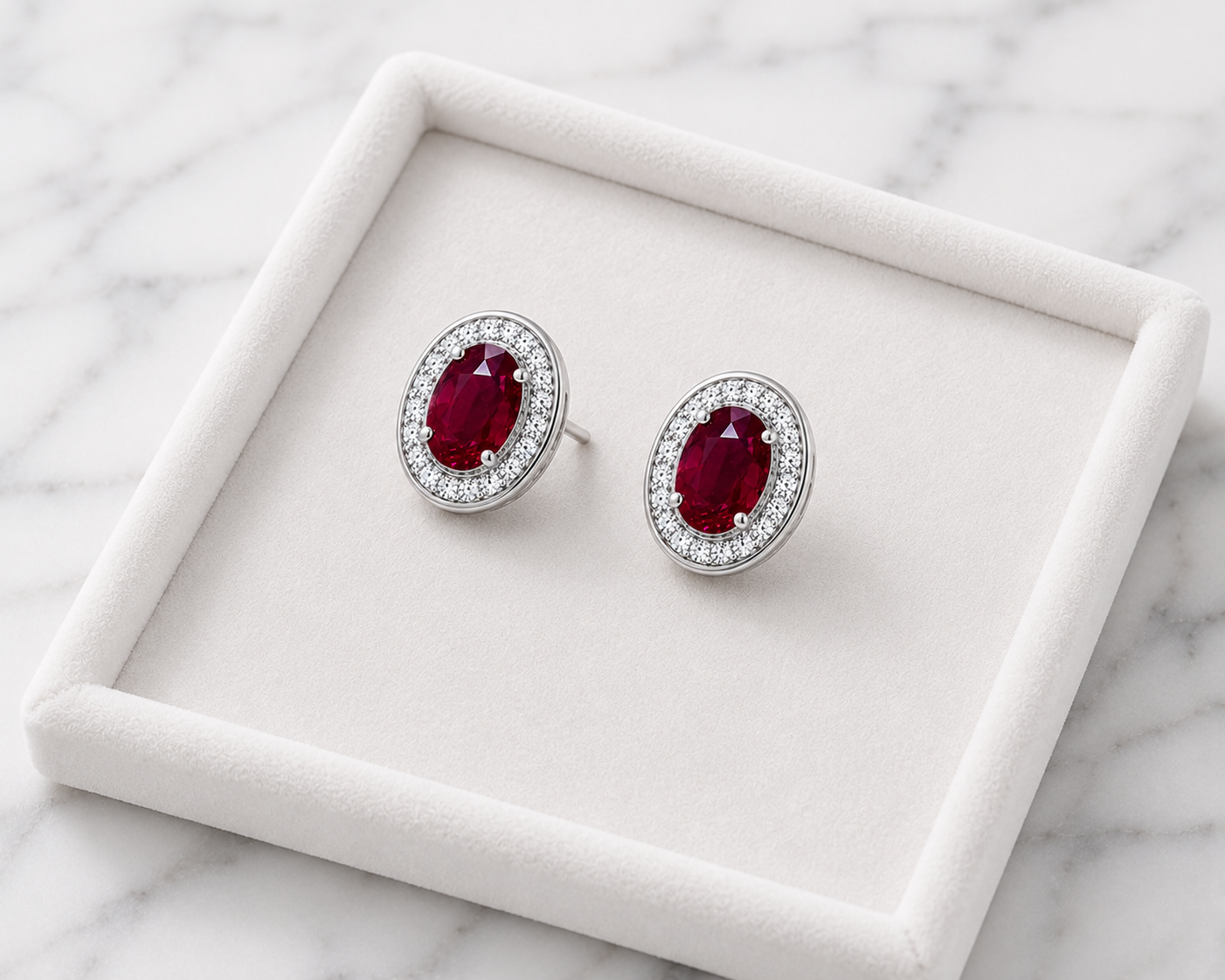 Natural 4x6mm oval ruby halo stud earrings in platinum plated 925 sterling silver with sparkling cubic zirconia on a white background.
