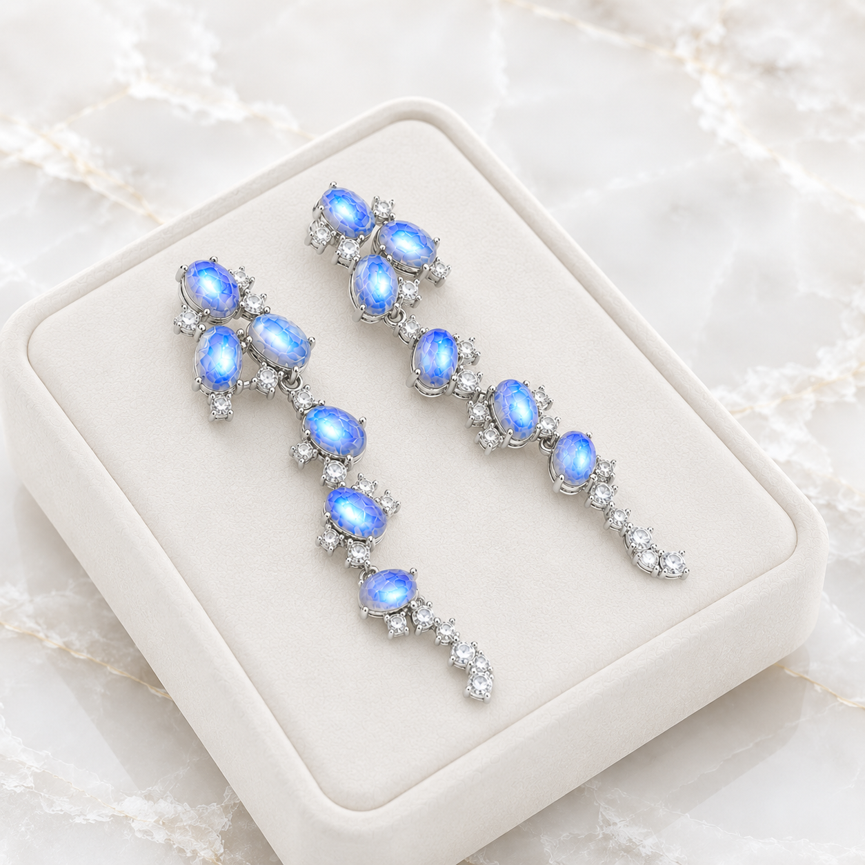 Natural Blue Moonstone stud earrings featuring genuine 4x6mm oval moonstones surrounded by high quality cubic zirconia in 925 sterling silver.