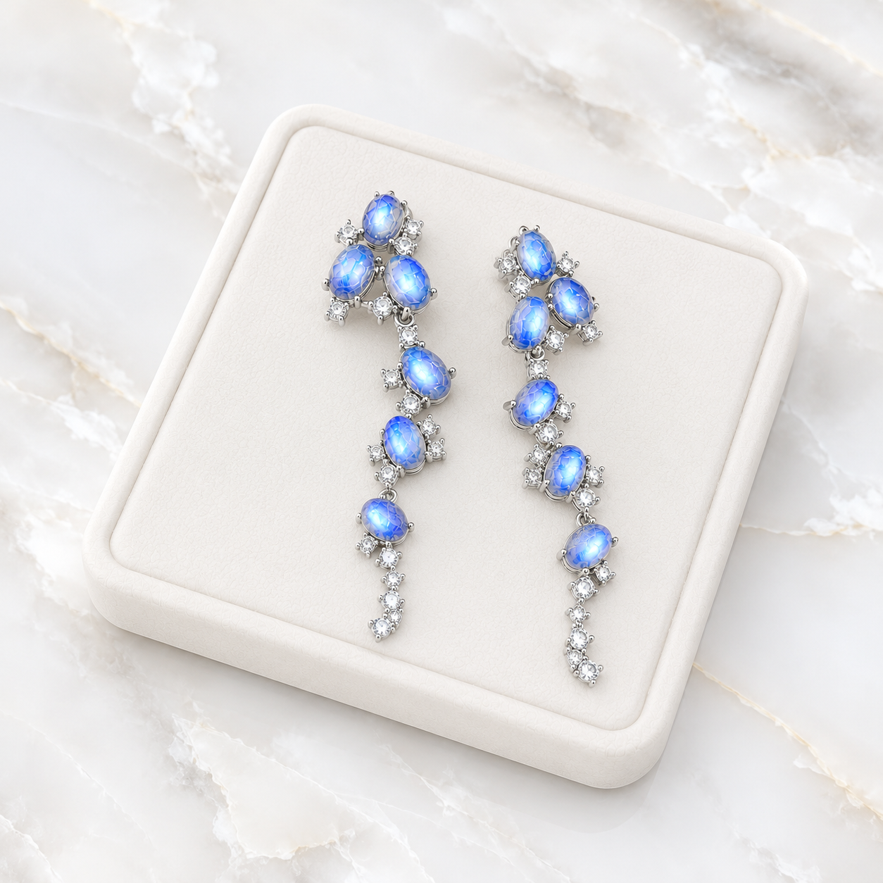 Natural Blue Moonstone stud earrings featuring genuine 4x6mm oval moonstones surrounded by high quality cubic zirconia in 925 sterling silver.