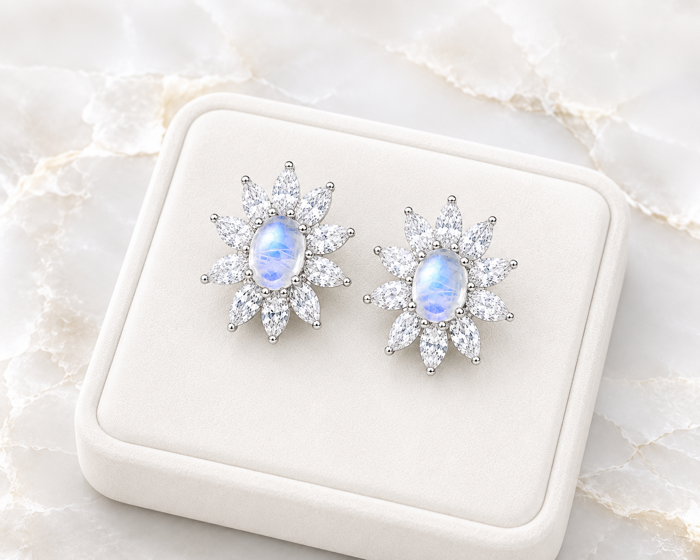 Blue Moonstone earrings displayed on a velvet tray over a marble table.