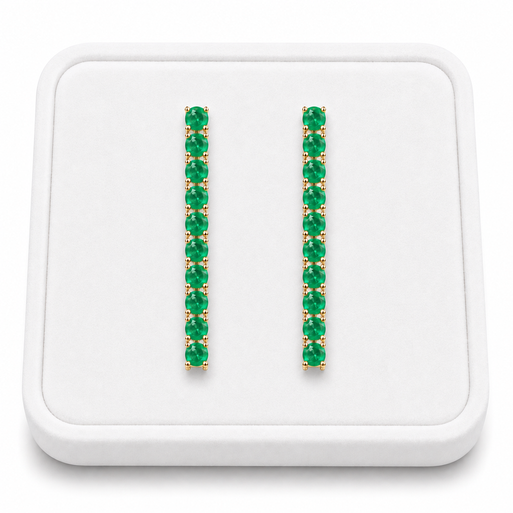 Phimsera natural emerald dangle earrings displayed on a white velvet jewelry tray against a bright white background