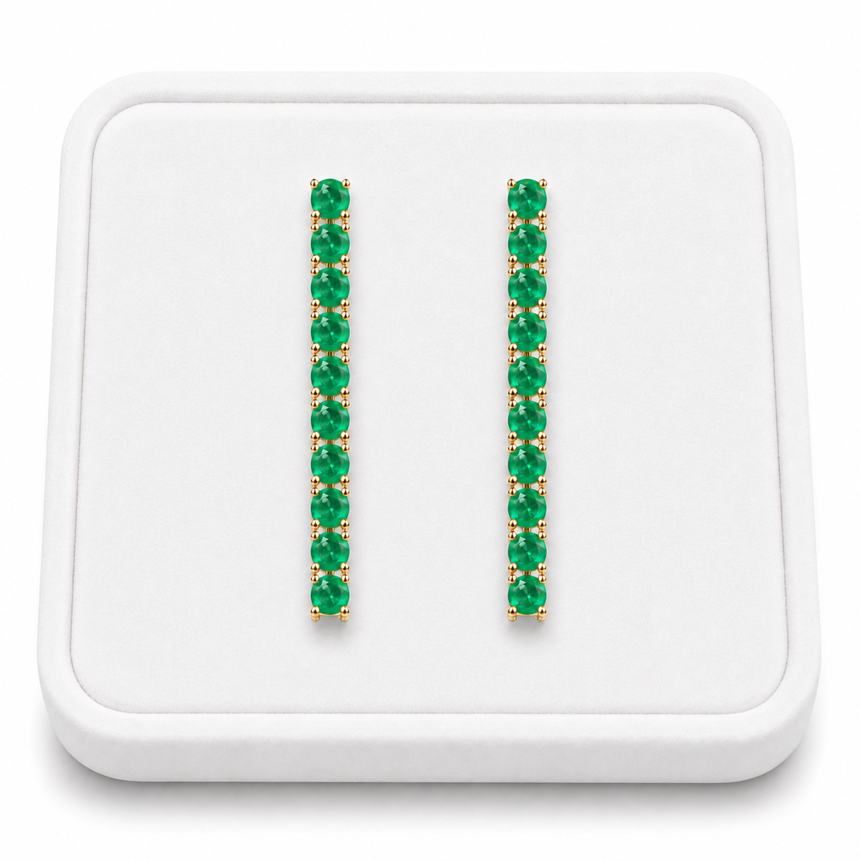 Phimsera natural emerald dangle earrings displayed on a white velvet jewelry tray against a bright white background