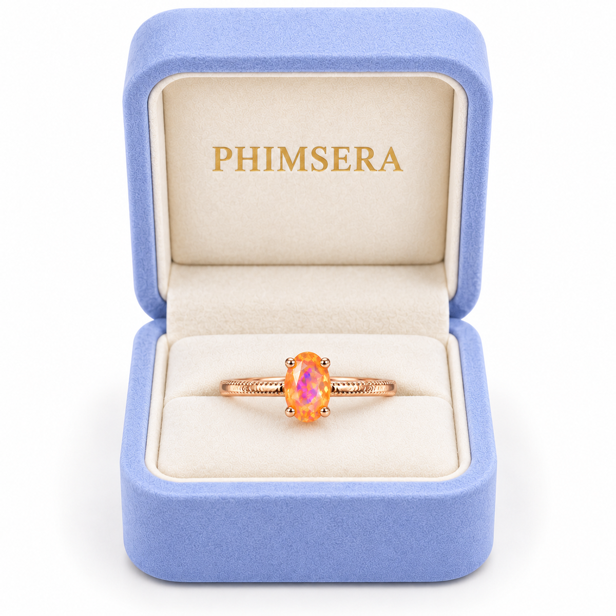 A rose gold ring with an oval iridescent opal center stone, presented in an open light blue velvet ring box with a cream interior. The inside lid of the box features the brand name 'PHIMSERA' in gold lettering.
