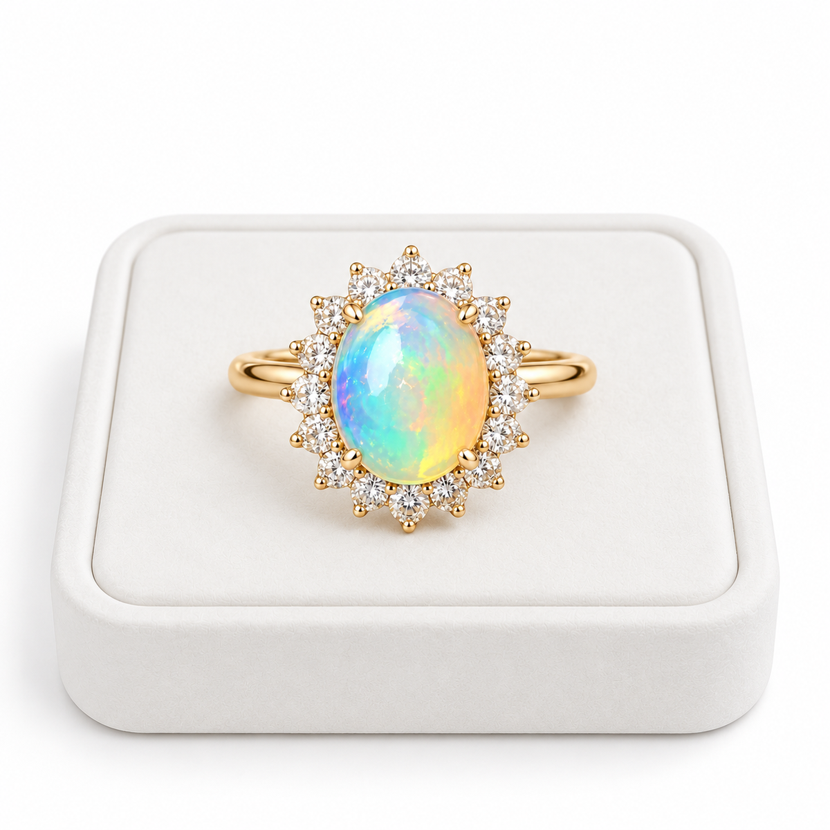 A yellow gold ring featuring a large oval iridescent opal center stone surrounded by a halo of small clear stones, displayed on a white ring box.