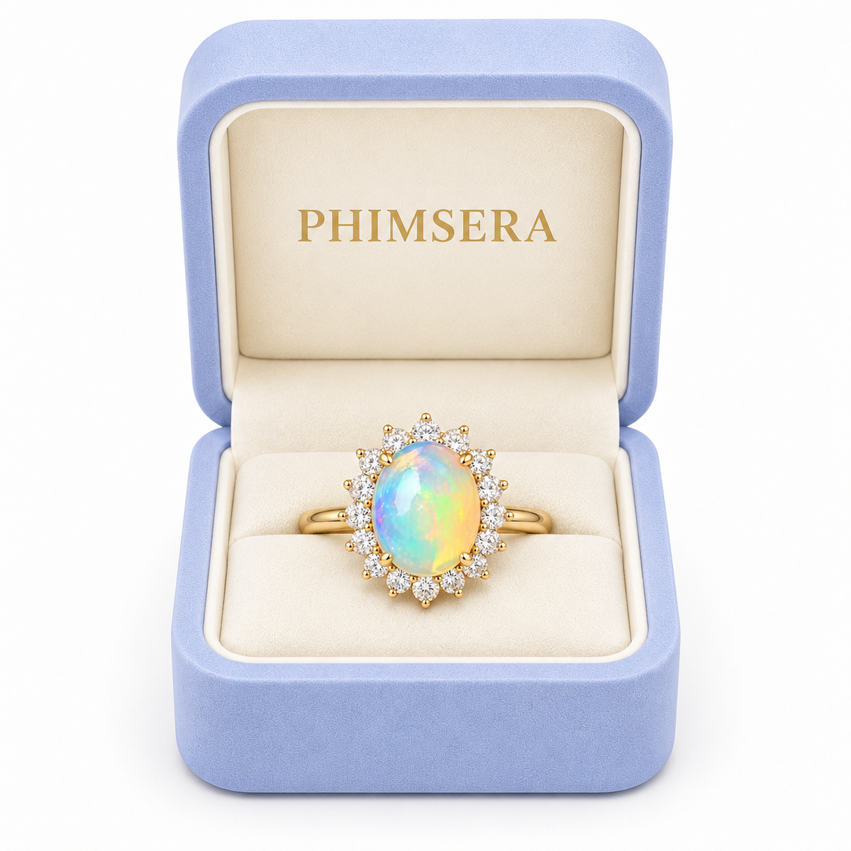A gold ring with an oval iridescent opal center stone and a halo of small clear stones, displayed in an open light blue jewelry box with the brand name PHIMSERA on the inside lid.