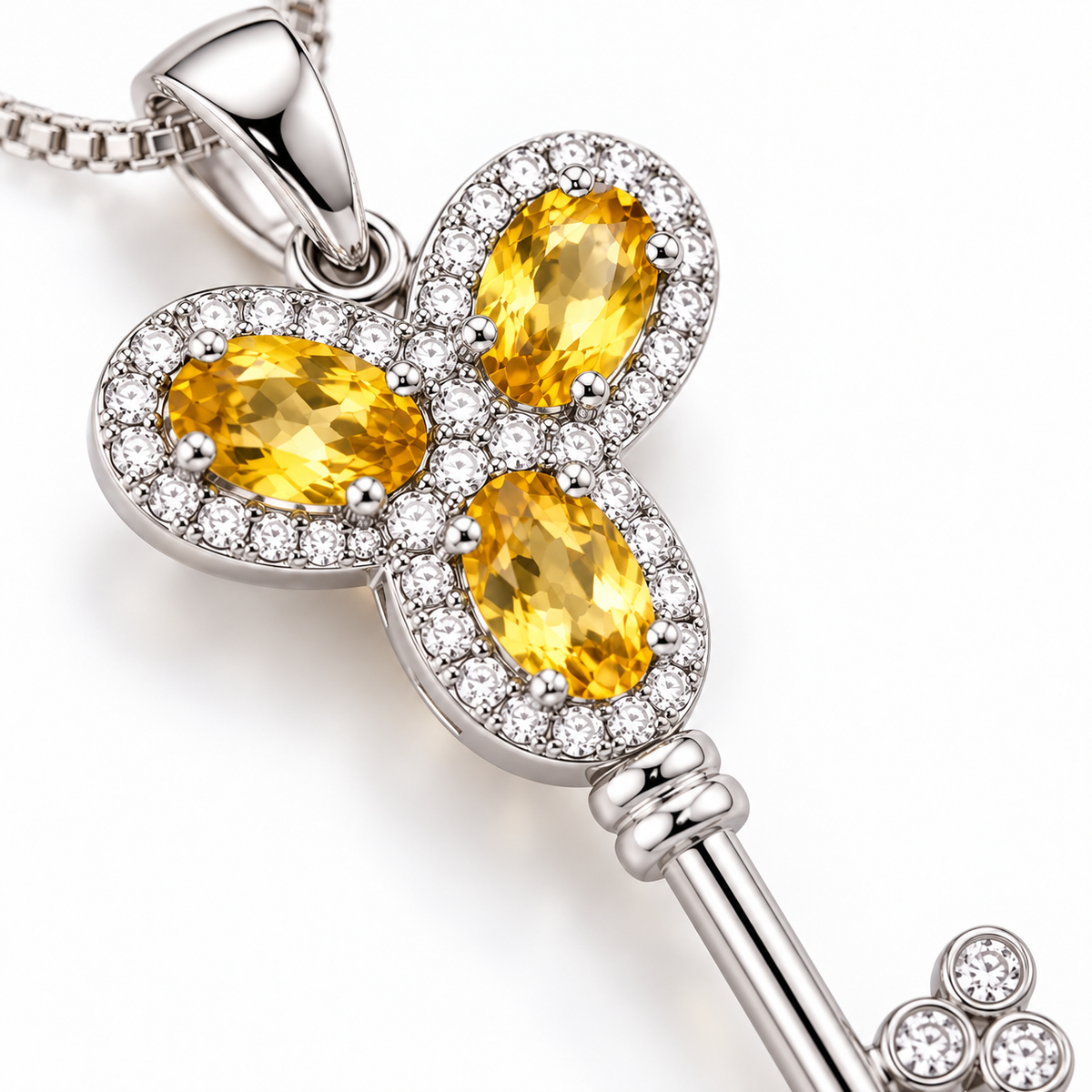Macro photograph of three natural 3x5mm golden-yellow citrine gemstones in the Phimsera Heavenly Key of Love and Peace necklace with detailed 925 Sterling Silver settings and surrounding accent stones.