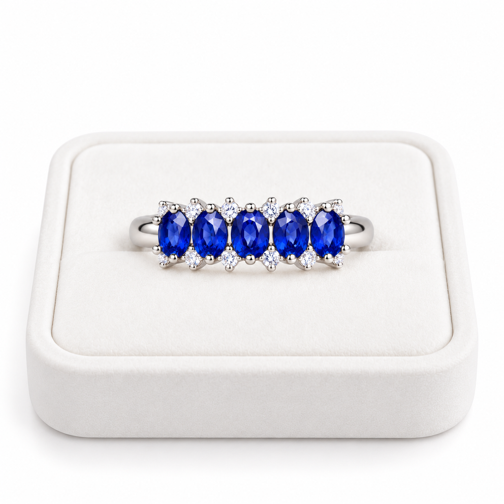 Natural blue sapphire band ring with 3×4mm oval gemstones displayed on a white velvet jewelry tray