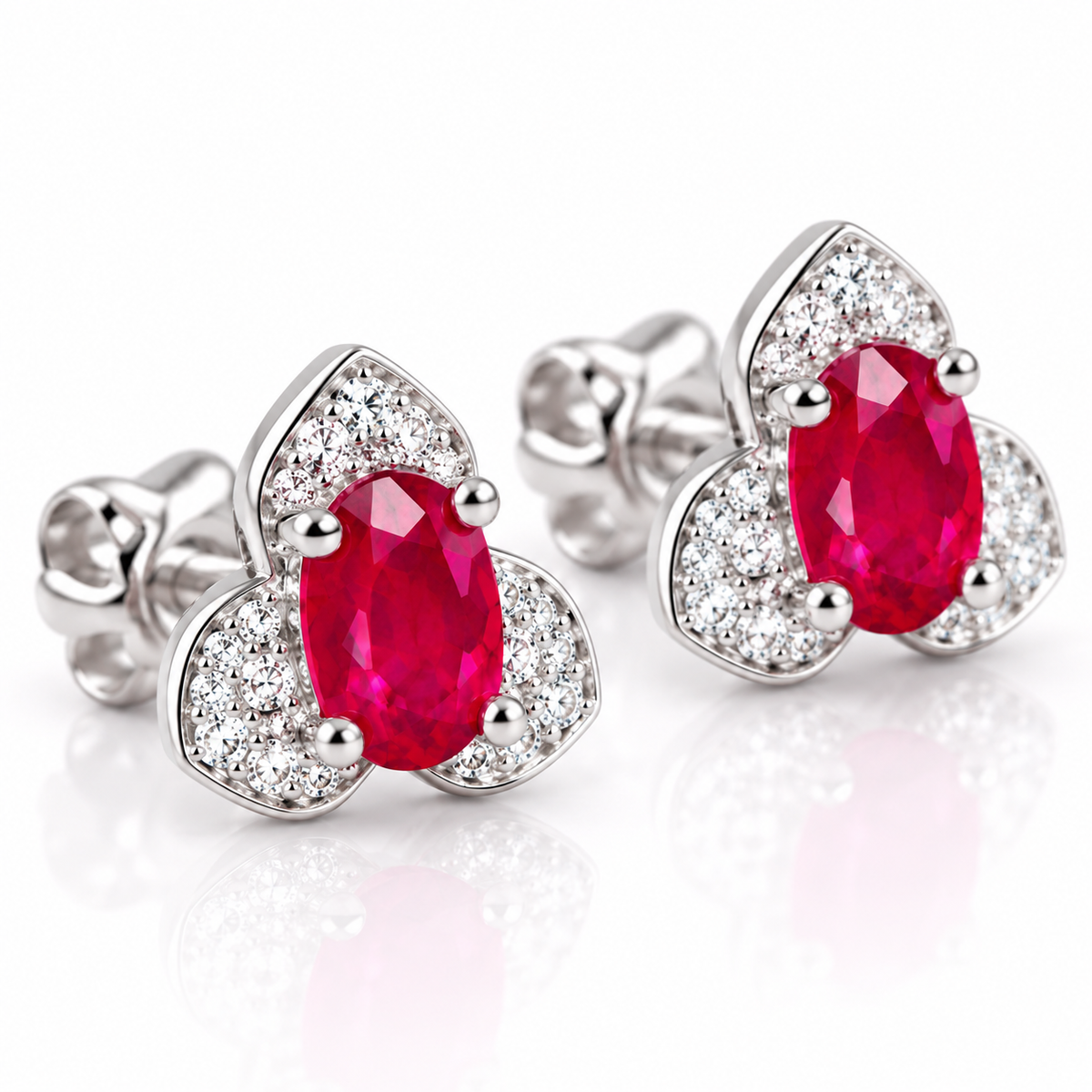Phimsera natural ruby stud earrings shown at a 45-degree angle with 4×6mm oval red gemstones and surrounding cubic zirconia accents