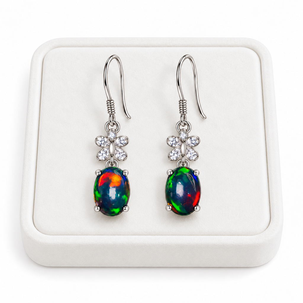 Natural black fire opal dangle earrings with 5x7mm gemstones displayed on a white velvet jewelry tray