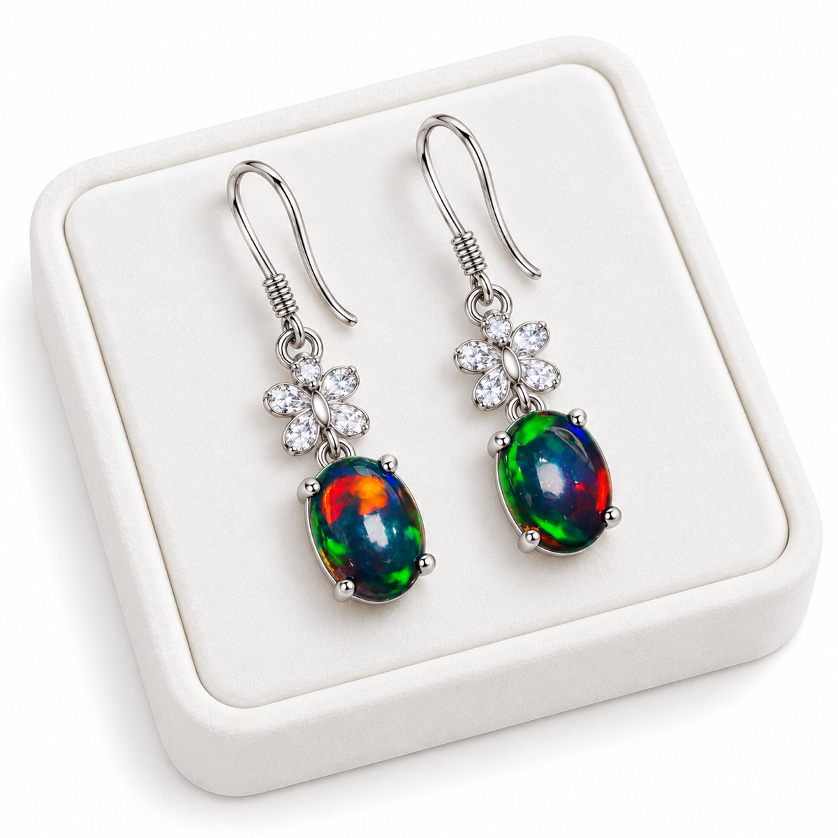 Natural black fire opal dangle earrings with 5x7mm gemstones displayed on a white velvet jewelry tray
