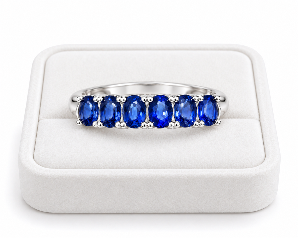 Natural blue sapphire band ring displayed on a white velvet jewelry tray by Phimsera