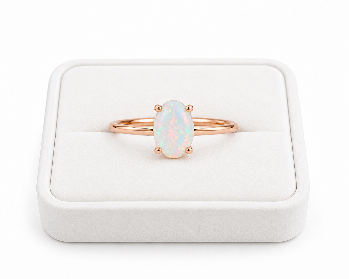 5x7mm natural opal solitaire ring displayed on a white velvet jewelry tray