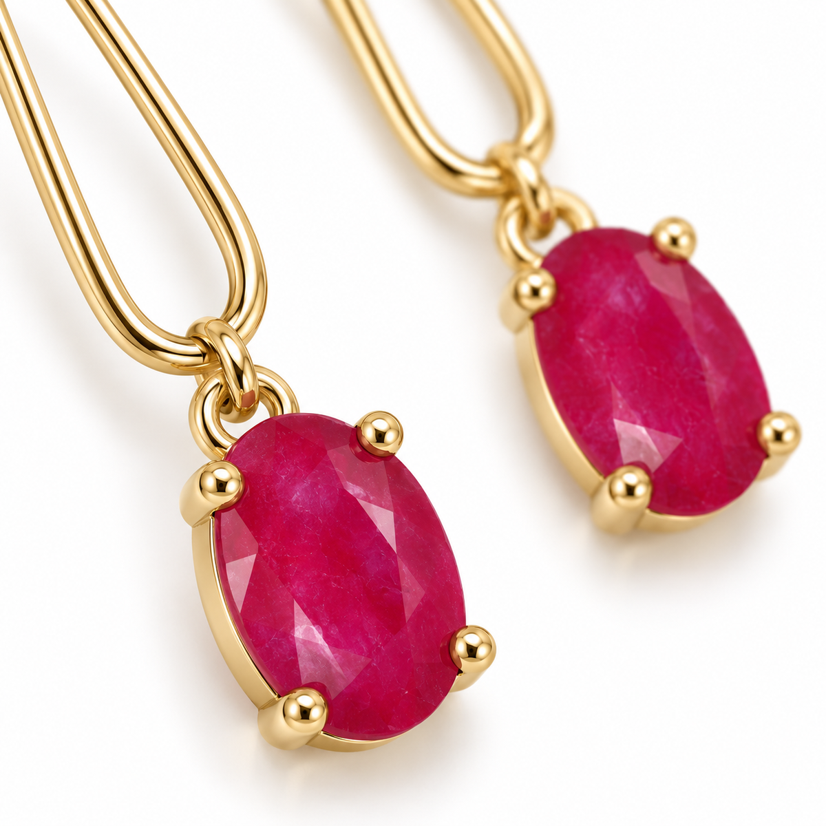 Macro detail of a natural 4 × 6 mm oval ruby gemstone in a Phimsera drop earring, showing its vivid pinkish-crimson color and opaque-to-semi-opaque appearance.