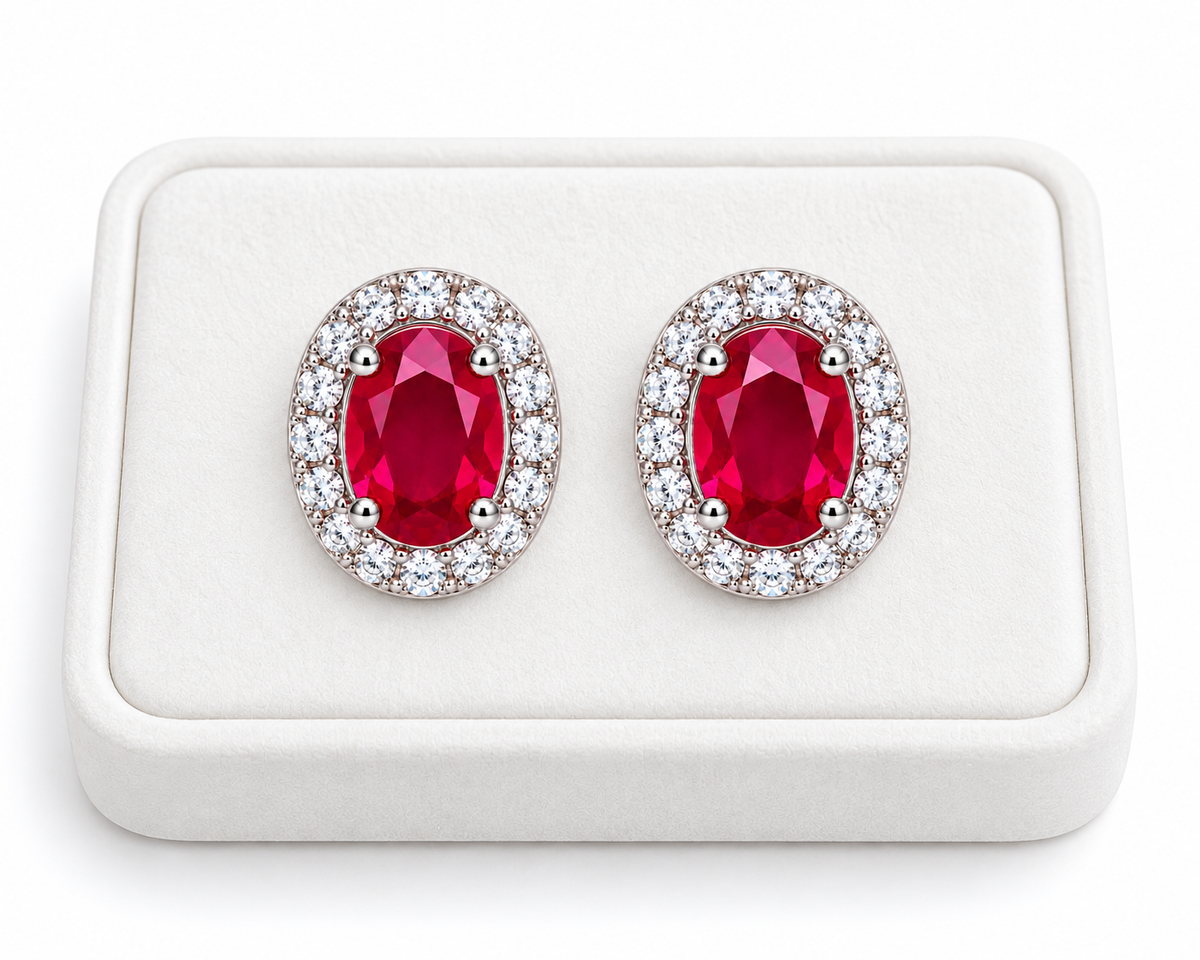 Natural ruby oval halo stud earrings displayed on a white velvet jewelry tray against a clean white background.