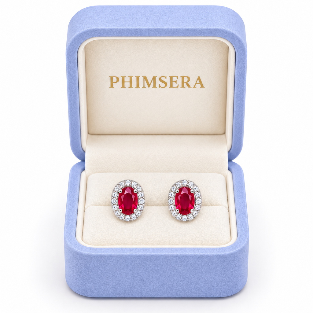 Phimsera natural ruby oval halo stud earrings displayed inside a branded periwinkle and cream jewelry gift box.