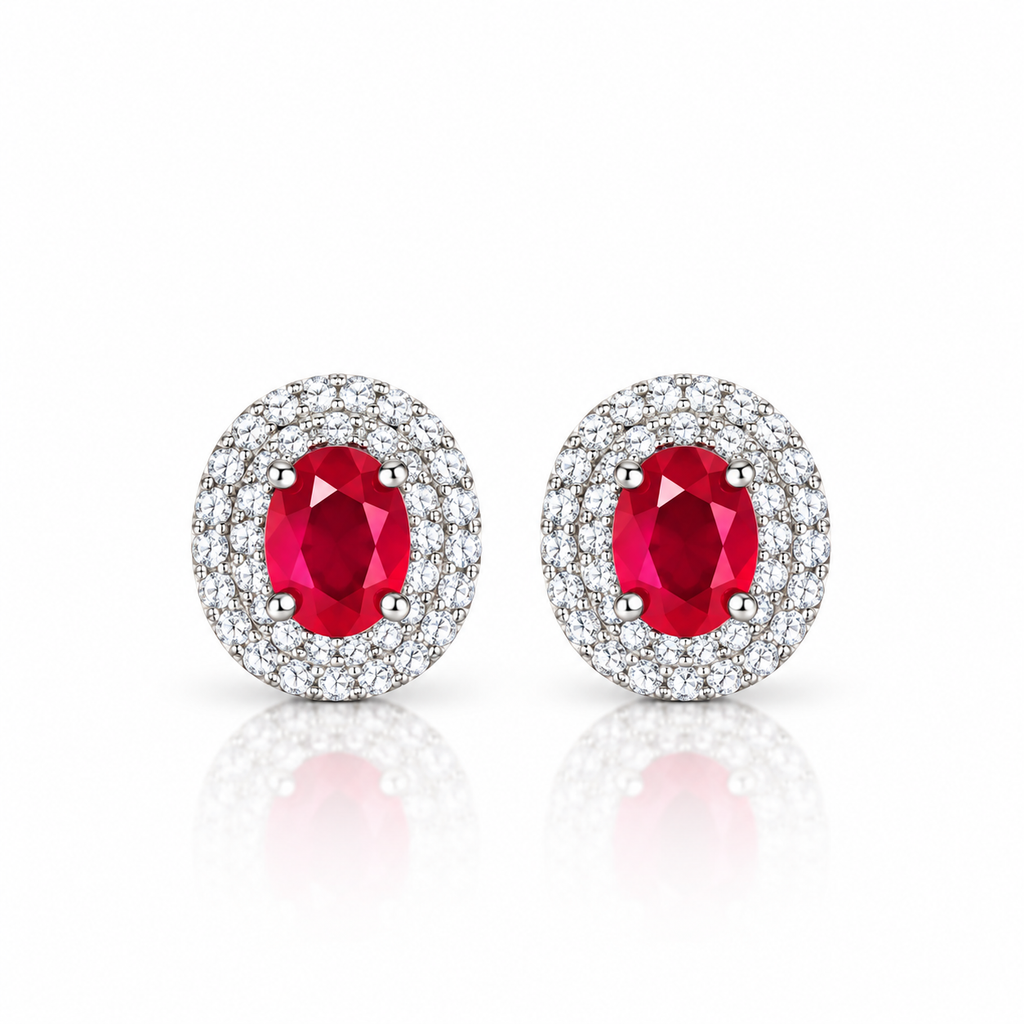 Phimsera natural ruby stud earrings featuring 4×5mm oval red ruby gemstones surrounded by cubic zirconia halos in 925 Sterling Silver on a white background.