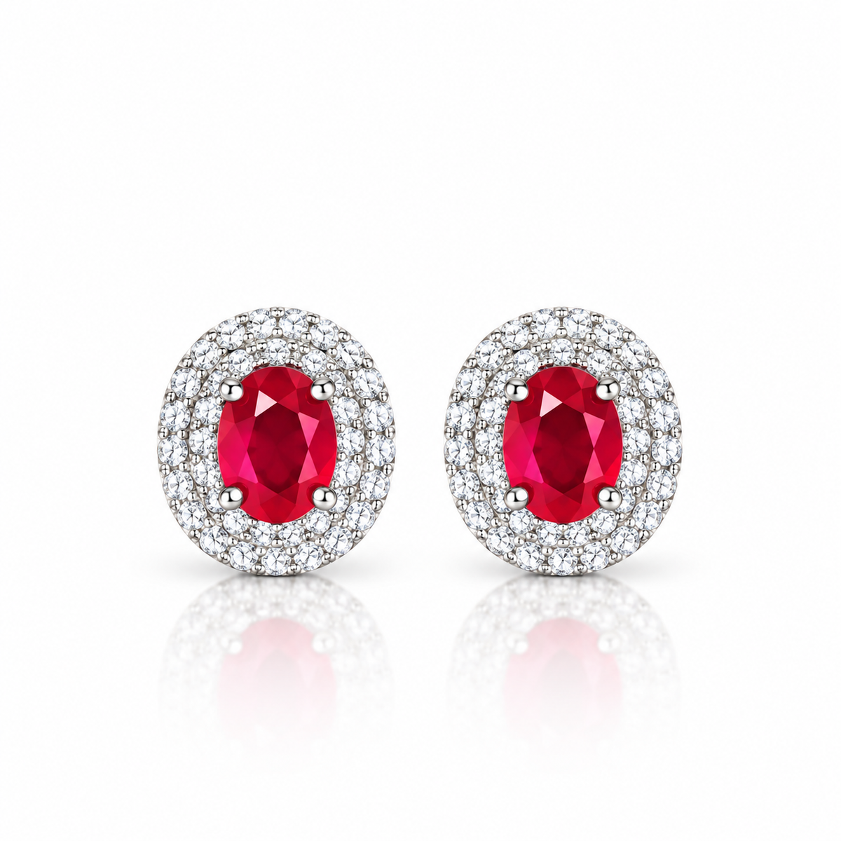 Phimsera natural ruby stud earrings featuring 4×5mm oval red ruby gemstones surrounded by cubic zirconia halos in 925 Sterling Silver on a white background.
