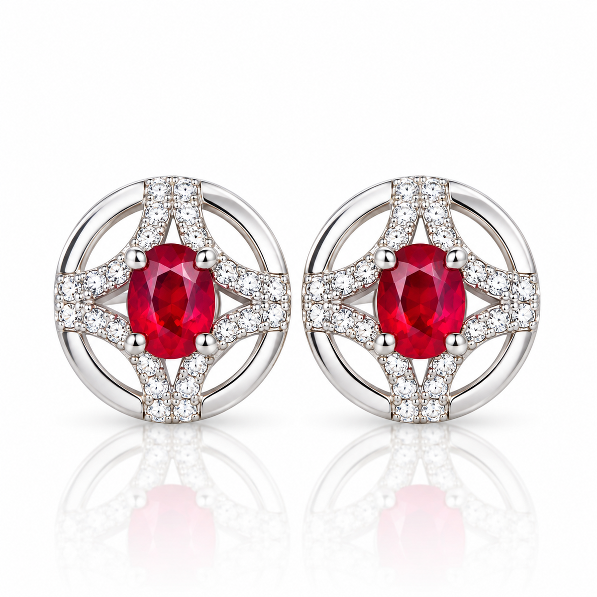 Natural ruby stud earrings featuring matching 3 × 4mm oval red ruby gemstones in circular openwork settings with clear accent stones on a white background.