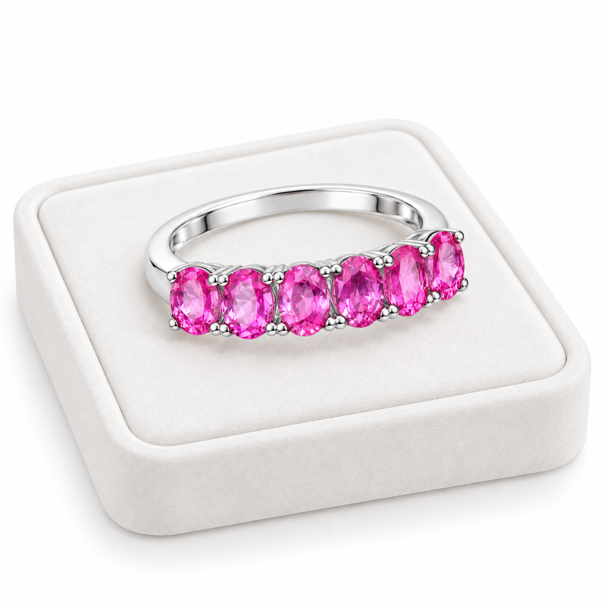 Natural pink sapphire band ring with 3x4mm gemstones displayed on a white velvet jewelry tray.