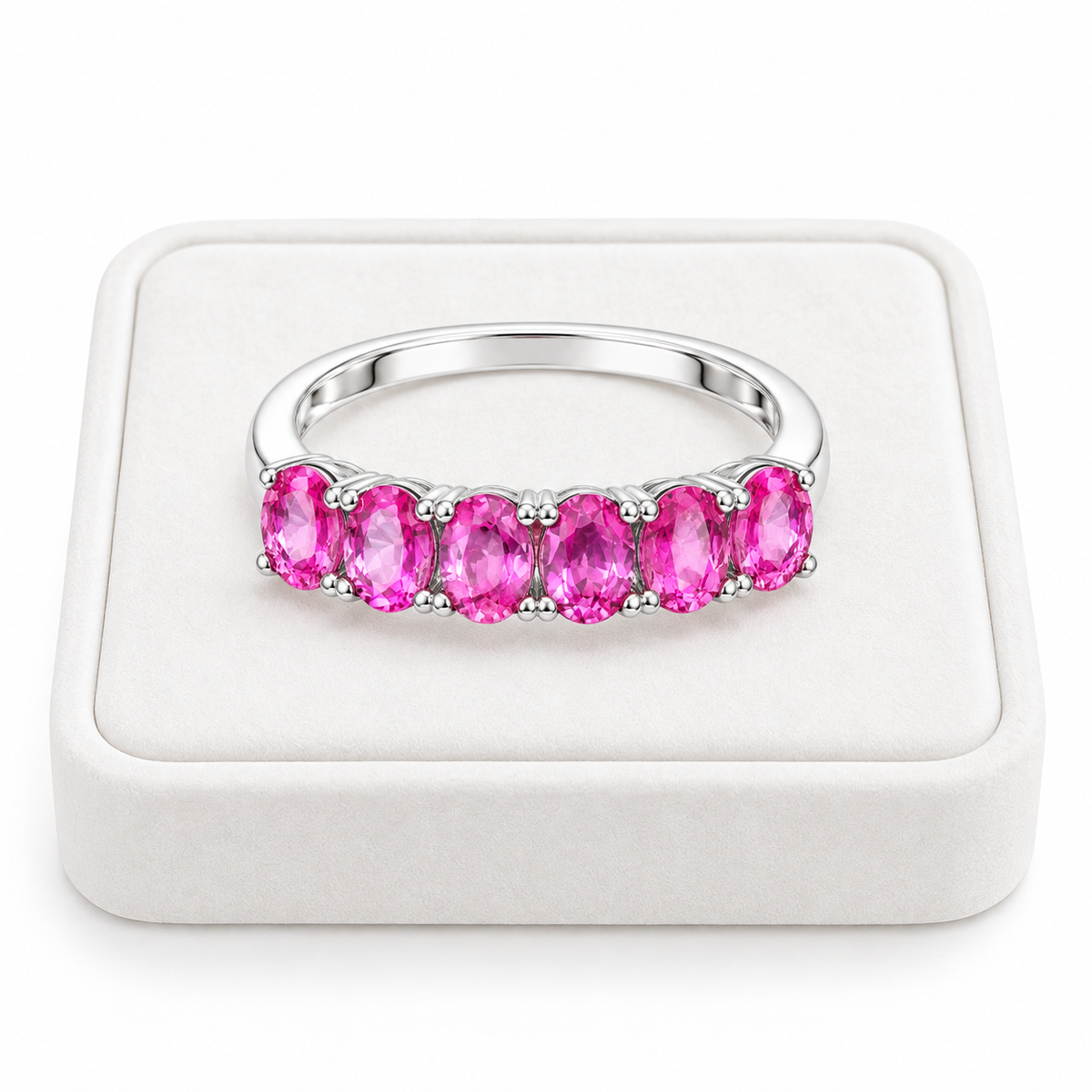 Natural pink sapphire band ring with 3x4mm gemstones displayed on a white velvet jewelry tray.