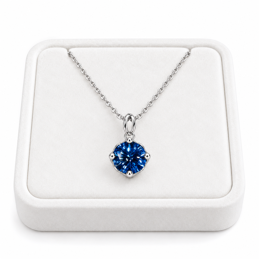 2 carat deep blue moissanite solitaire necklace arranged on a premium white velvet jewelry tray with a delicate sterling silver chain and brilliant 8mm royal-blue round gemstone against a pure white background.