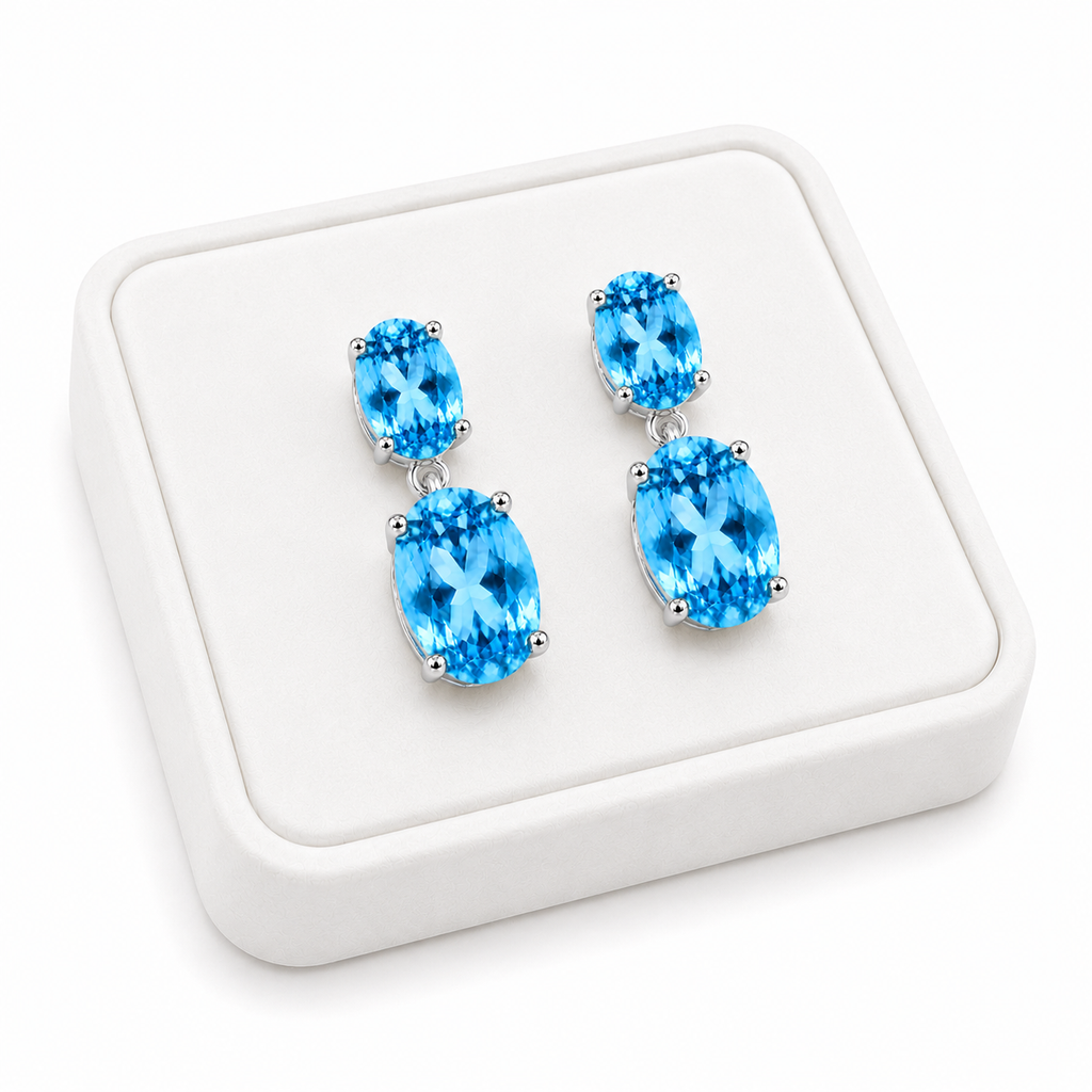 Close-up of faceted Swiss Blue Topaz gemstones in elegant sterling silver dangle earrings on a White Tray