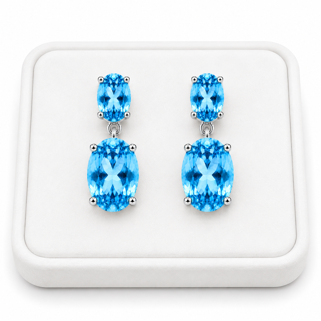 Close-up of faceted Swiss Blue Topaz gemstones in elegant sterling silver dangle earrings on a White Tray