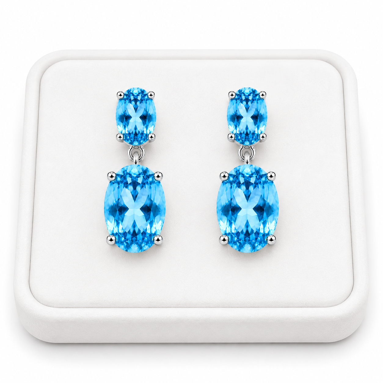 Close-up of faceted Swiss Blue Topaz gemstones in elegant sterling silver dangle earrings on a White Tray