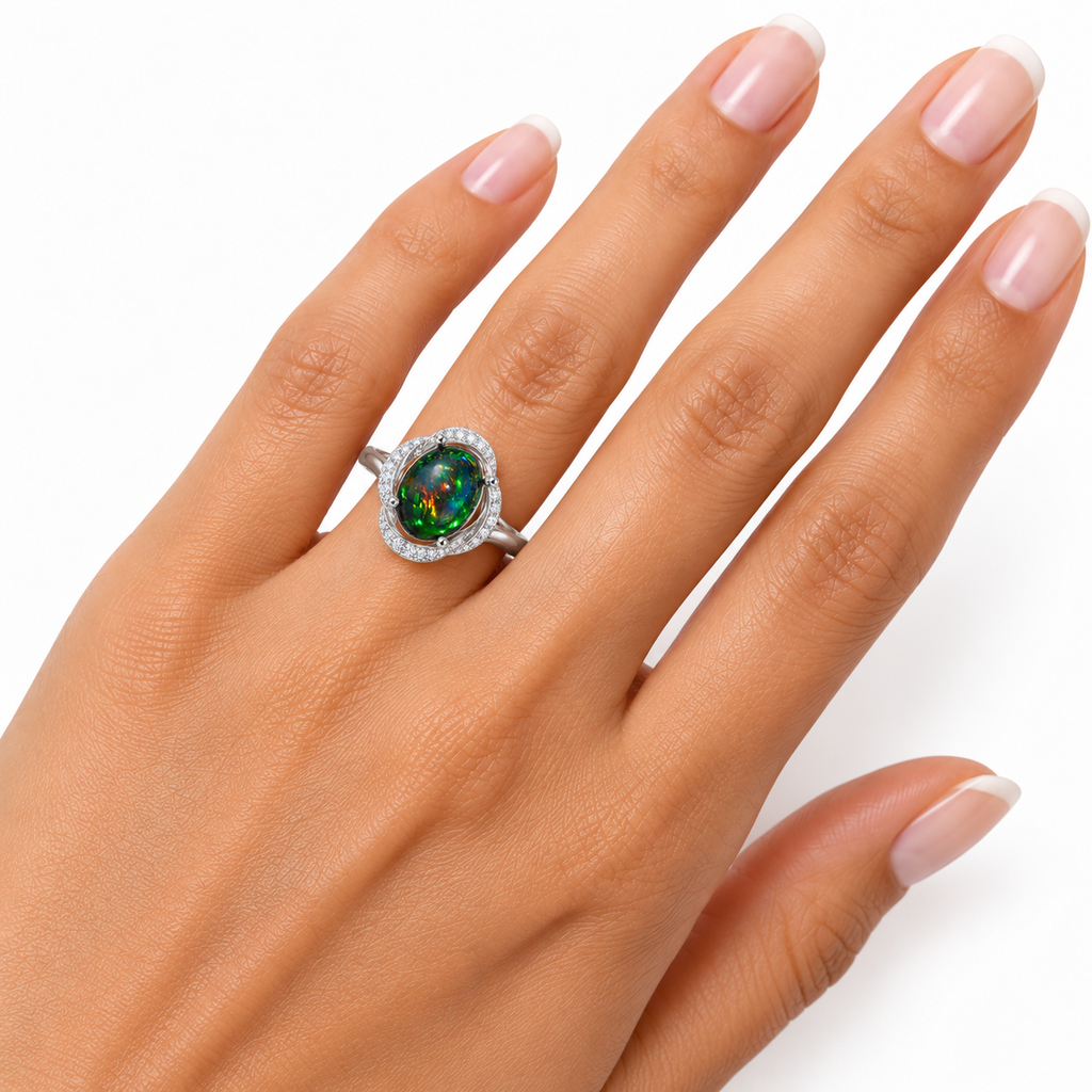 Australian dyed-black fire opal halo ring worn on a ring finger, showing its oval center stone and colorful flashes.