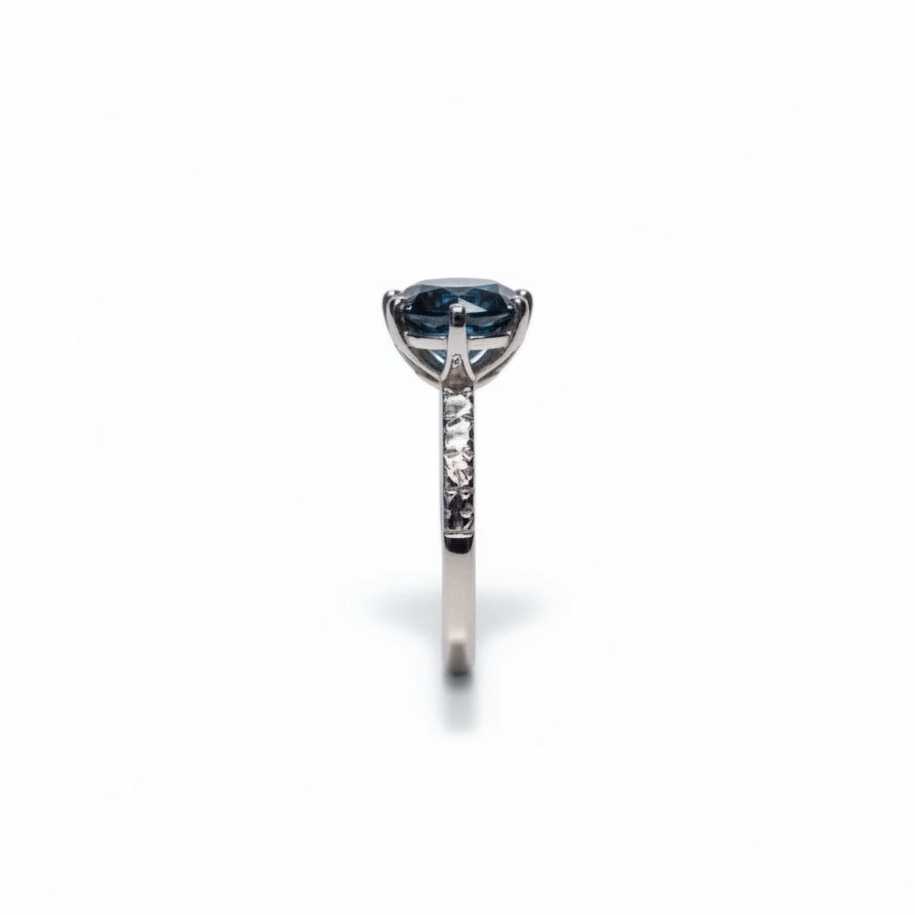 2 carat dark blue round moissanite solitaire ring in platinum plated 925 sterling silver on a white background