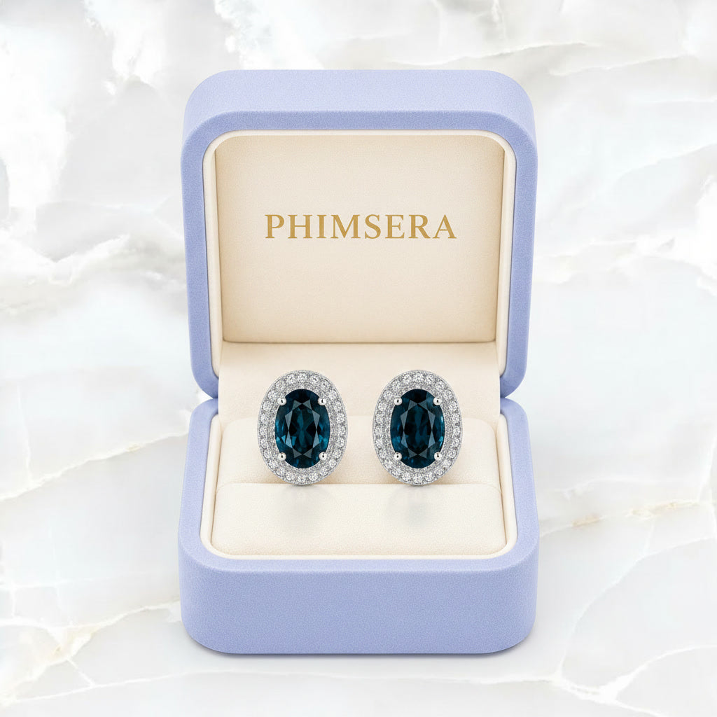 Natural London Blue Topaz oval stud earrings with 5x7mm gemstones, double halo cubic zirconia, platinum-plated 925 sterling silver, front view.