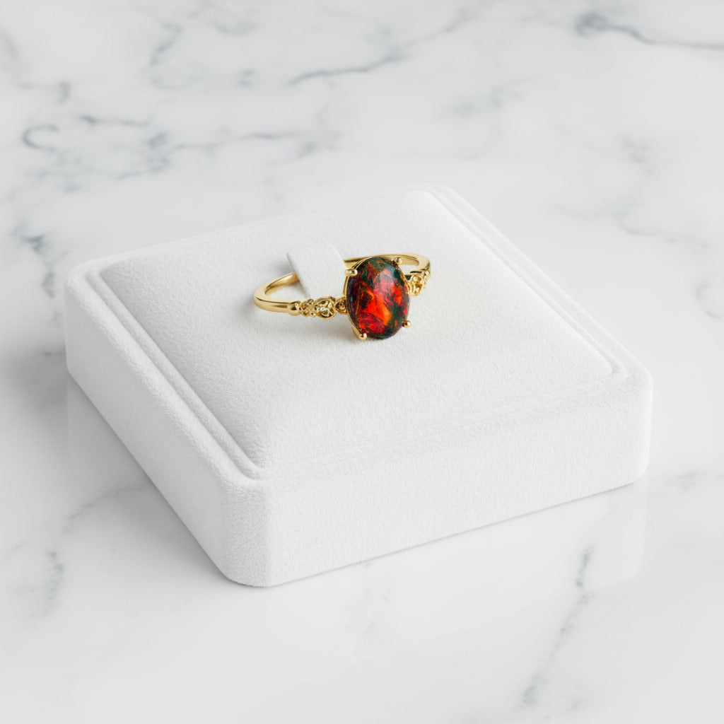 Australian Black Fire Opal ring featuring a 3 CT 8x10mm oval Australian opal with brilliant red fire in a sterling silver setting with gold plating and decorative shoulders.