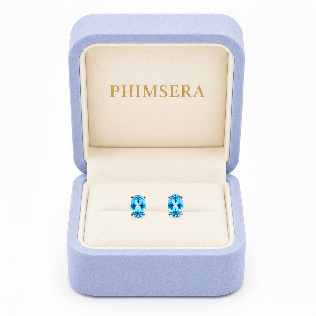 Natural 4x6mm oval Swiss Blue Topaz solitaire stud earrings in Rose Gold Plated 925 sterling silver on a white background in Phimsera box