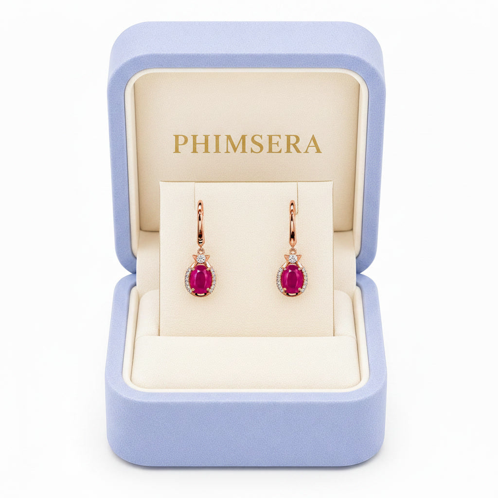 Natural bright pink opaque ruby drop earrings with 6x8mm oval gemstones, cubic zirconia halo, platinum plated 925 sterling silver on a white background.