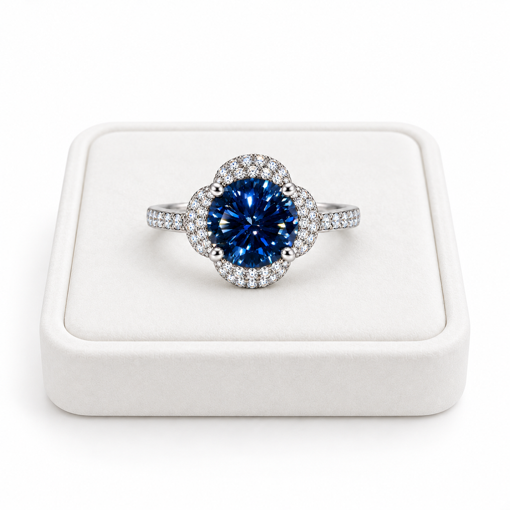 Phimsera 2 carat deep blue moissanite floral halo ring displayed on a premium white velvet jewelry tray against a pure white background, featuring an 8mm round brilliant center gemstone.