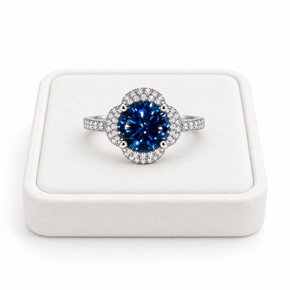 Phimsera 2 carat deep blue moissanite floral halo ring displayed on a premium white velvet jewelry tray against a pure white background, featuring an 8mm round brilliant center gemstone.