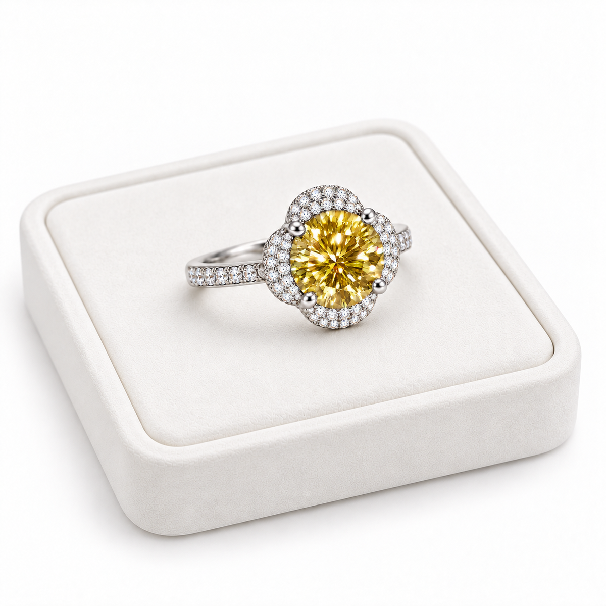 Angled view of an 8mm yellow moissanite floral halo ring resting on a slightly turned white velvet jewelry tray, showing the golden center gemstone and sparkling silver band.