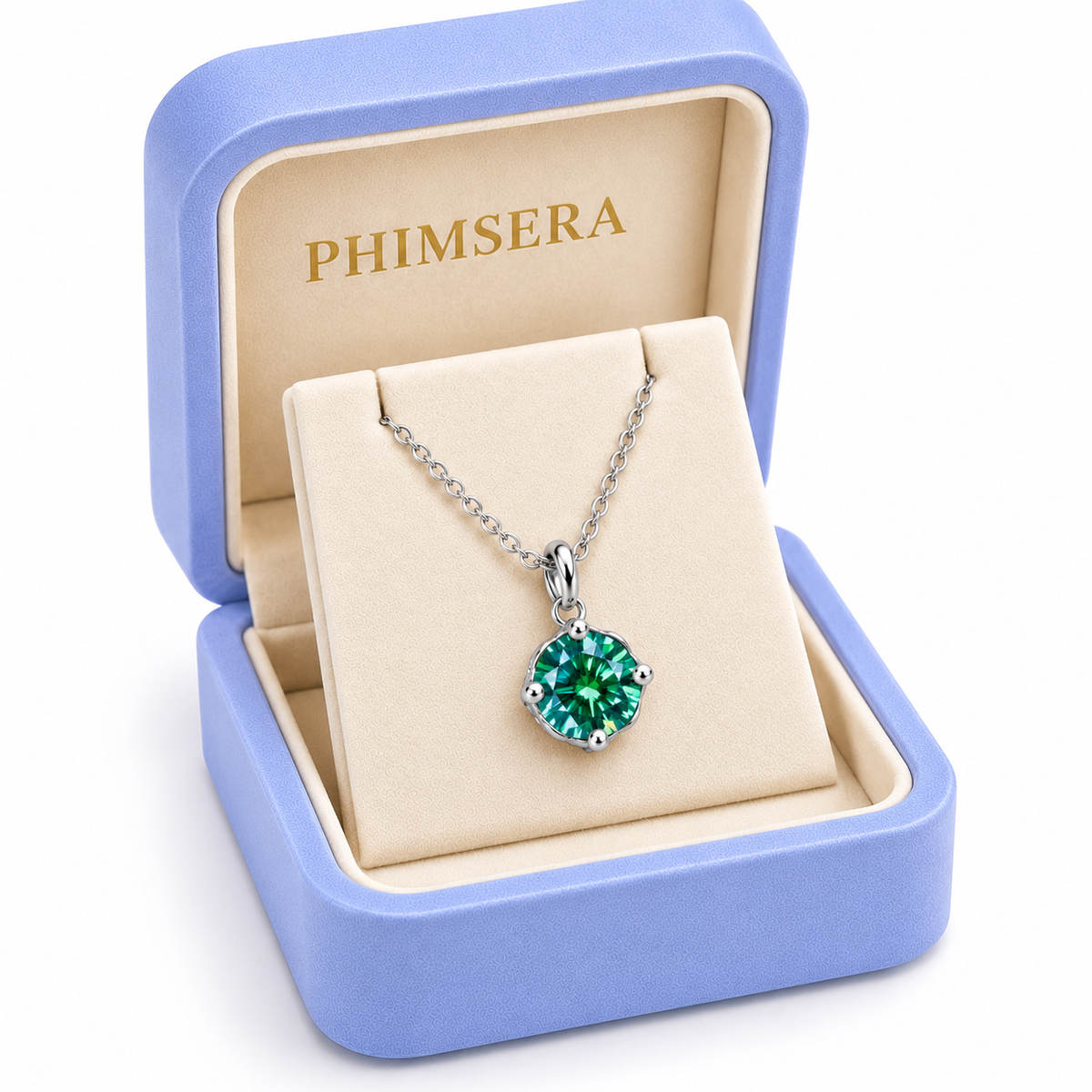 Angled view of a periwinkle Phimsera jewelry gift box containing an 8mm emerald green moissanite solitaire pendant necklace with a delicate silver chain, ivory jewelry insert, and gold Phimsera branding.