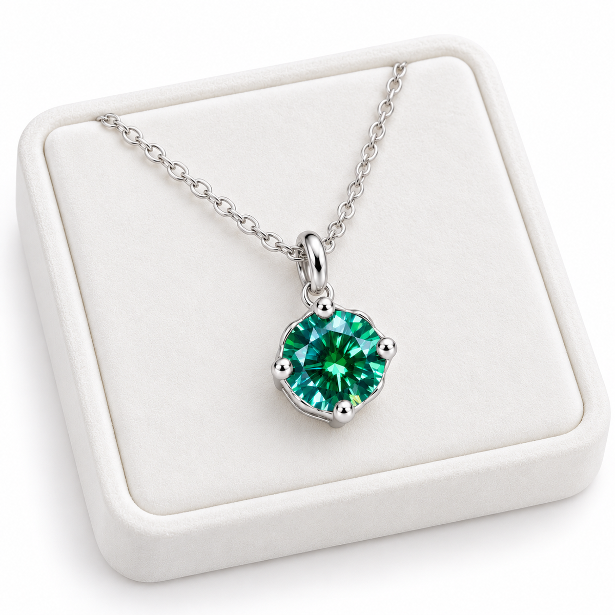 Angled white velvet jewelry tray displaying an 8mm round brilliant green moissanite pendant necklace with a four-prong sterling silver setting, delicate oval-link chain, and clean white background.