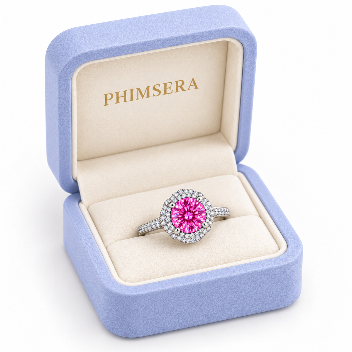 Three-quarter view of a 2 carat pink moissanite floral halo ring presented in a slightly turned periwinkle Phimsera jewelry box with cream velvet lining, gold branding and a pure white background.