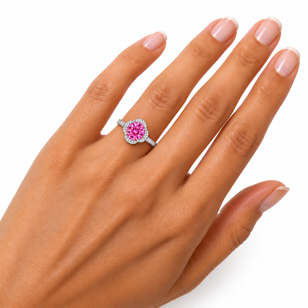 Close-up hand model photograph of an 8mm pink moissanite floral halo ring worn on the ring finger, showing delicate floral detailing, brilliant pink gemstone reflections and a slender pavé-accented silver band.