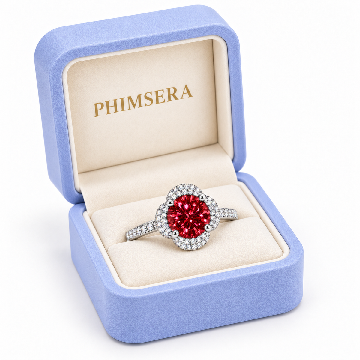 Three-quarter view of a 2 carat red moissanite floral halo ring presented in a slightly turned periwinkle Phimsera jewelry box with cream velvet lining, gold branding and a pure white background.