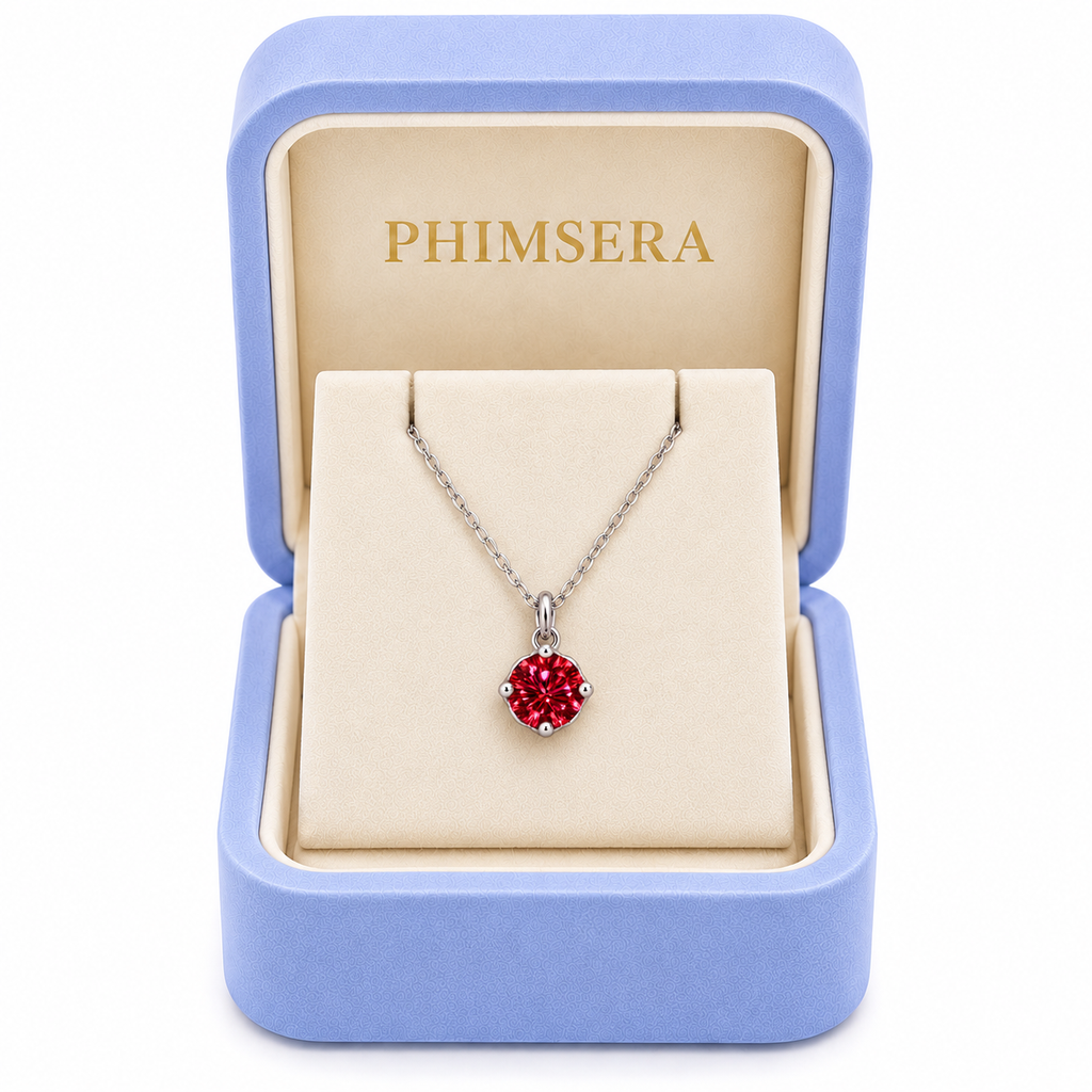 2 carat red moissanite solitaire necklace displayed inside an open periwinkle Phimsera jewelry gift box with an ivory interior, gold Phimsera logo, and clean white background.