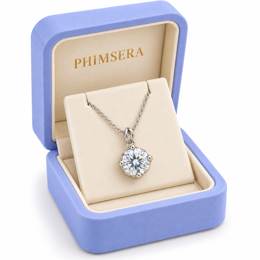 Angled presentation of a periwinkle Phimsera jewelry gift box containing an 8mm white moissanite solitaire pendant necklace with a delicate silver chain and ivory jewelry insert.