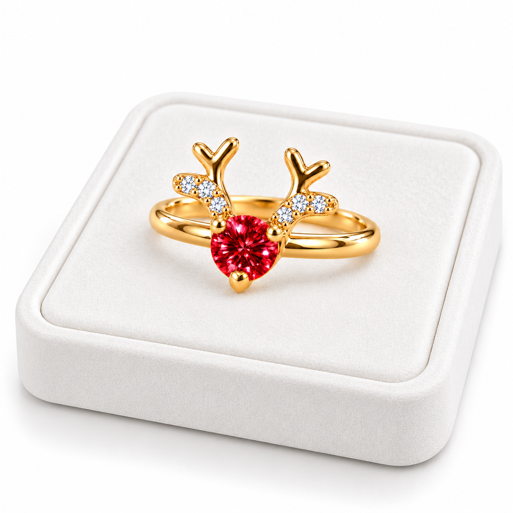 Angled white velvet jewelry tray displaying a gold-plated sterling silver Christmas reindeer ring with a vivid red moissanite gemstone, sculpted golden antlers, and sparkling CZ accents.