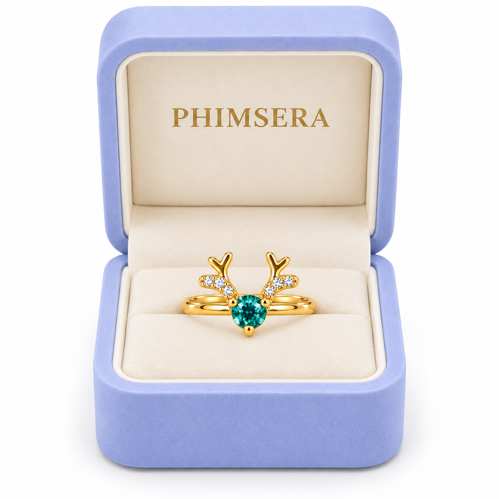 Phimsera green moissanite Christmas reindeer antler ring displayed in an open periwinkle jewelry gift box with ivory interior and gold Phimsera branding.